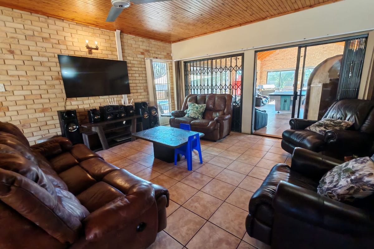 Spacious living room featuring exposed brick walls, timber-clad ceiling, ceiling fan, and large sliding glass doors opening to an outdoor patio area.