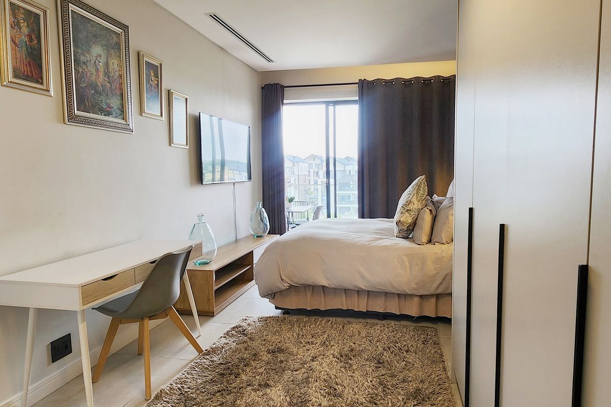 A well-maintained bedroom featuring built-in cupboards, ducted air conditioning, and sliding glass doors leading to a private balcony.