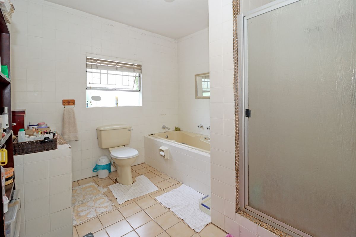 A dated bathroom featuring a built-in bathtub, separate shower enclosure, and tiled flooring. The space offers a functional layout ready for modernization.
