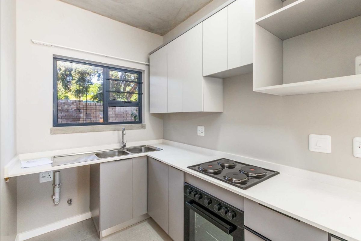 Modern kitchen featuring sleek grey cabinetry, white countertops, a built-in oven with electric hob, and a double stainless steel sink.
