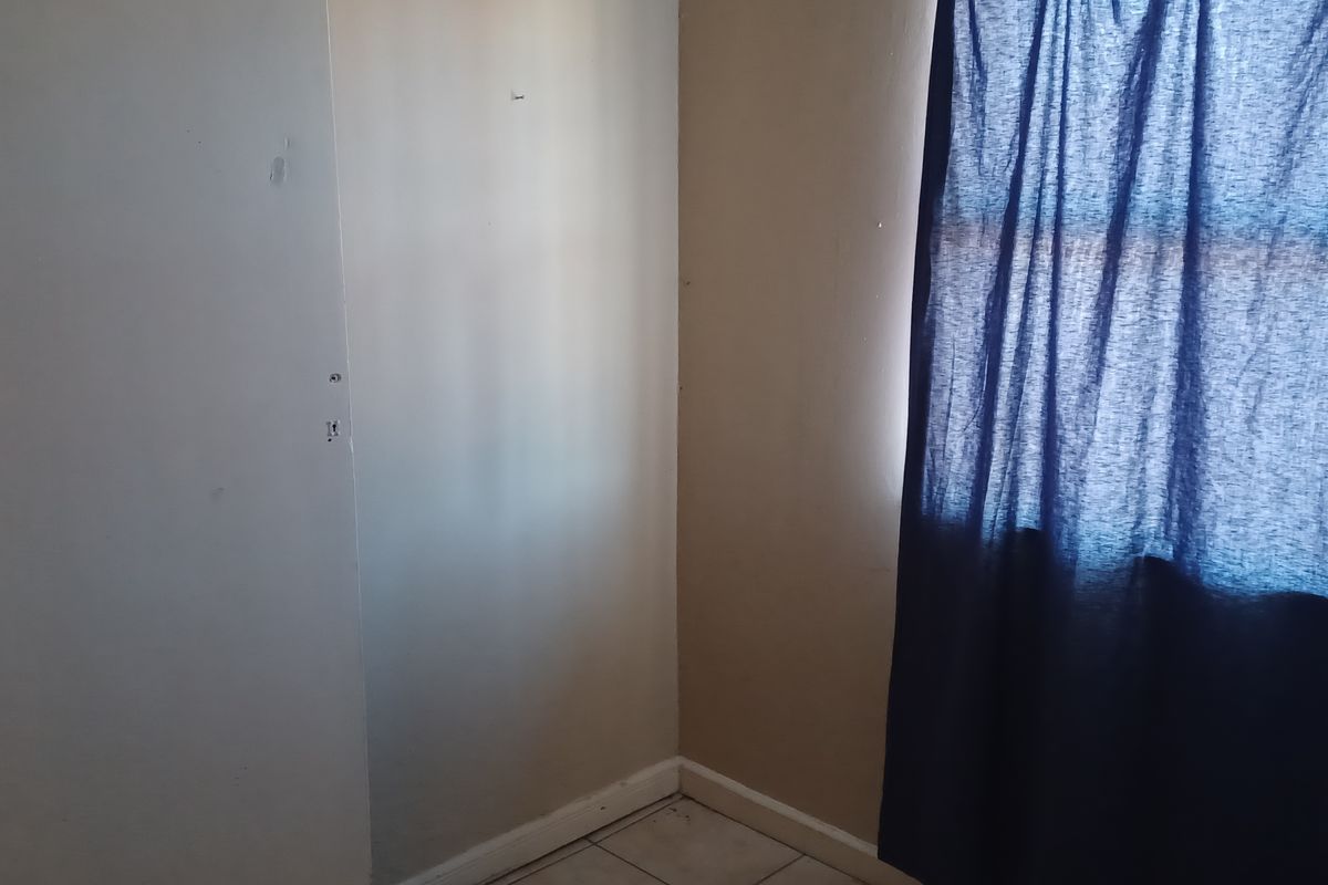 An empty bedroom corner featuring tiled flooring and neutral wall tones, offering a blank canvas for potential interior updates.