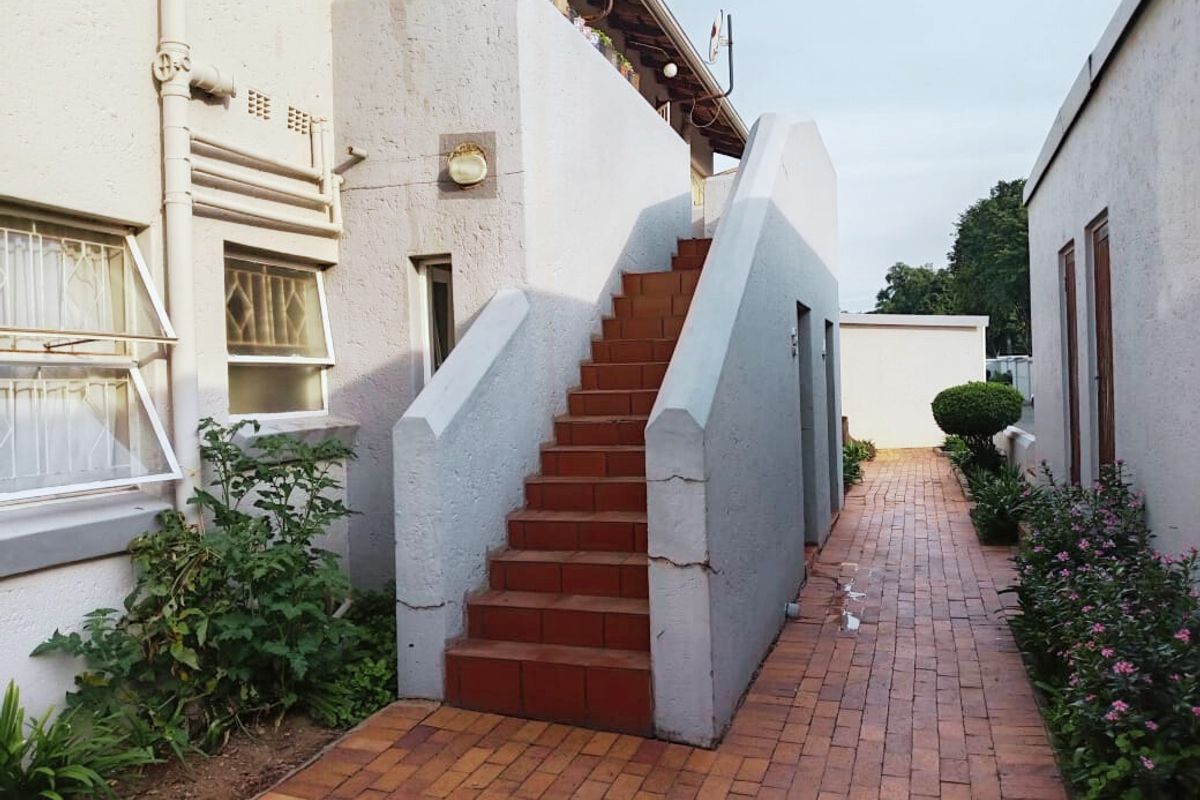 Exterior view of an apartment complex featuring a brick-paved walkway and a set of external stairs leading to an upper level.