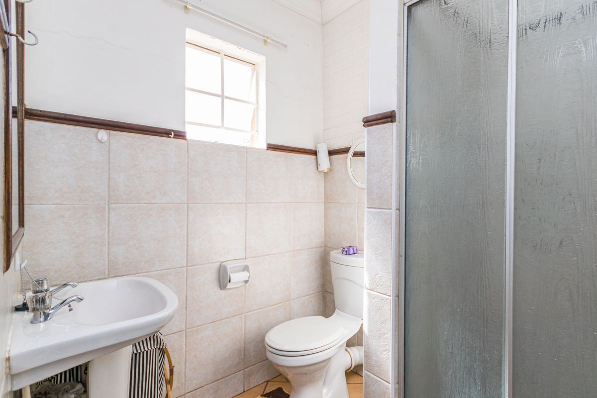 Compact bathroom featuring a pedestal basin, toilet, and shower enclosure with tiled walls and flooring.
