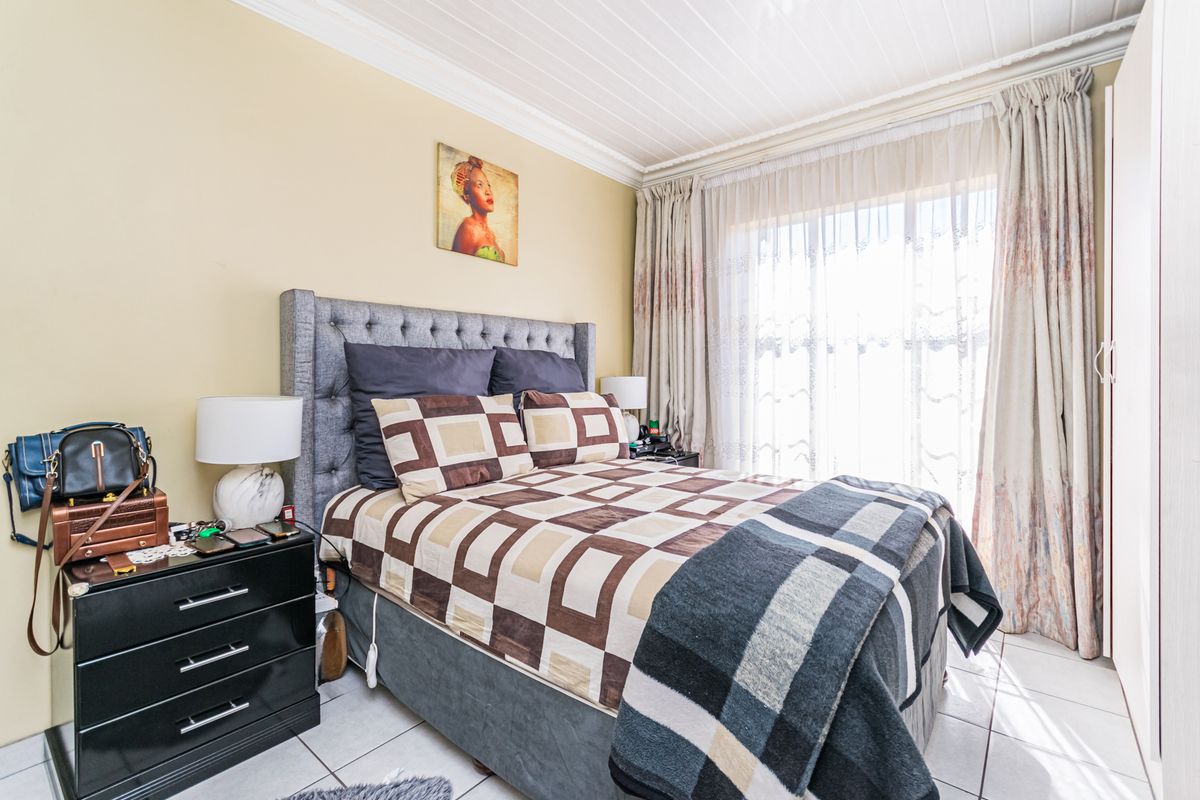 A cozy bedroom featuring tiled flooring, a built-in wardrobe, and classic crown molding, with natural light streaming through the window.