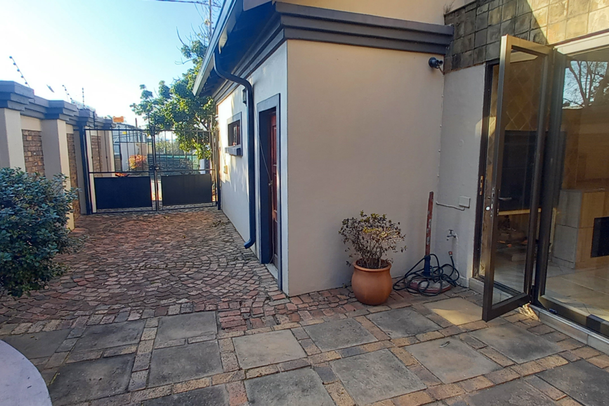 Rear courtyard area featuring cobblestone paving, secure boundary walls with electric fencing, and access to the interior via sliding glass doors.