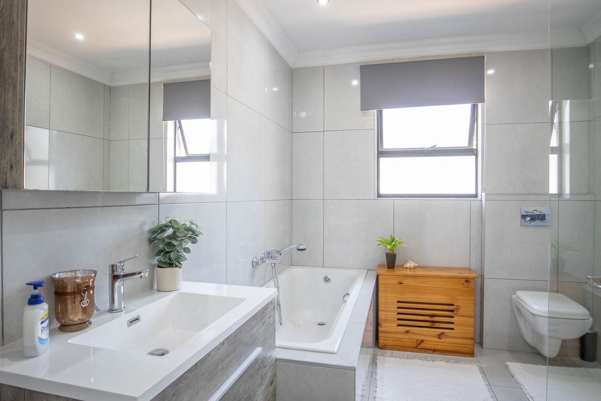 Modern bathroom featuring a built-in vanity, wall-hung toilet, tiled finishes, and a built-in bathtub with contemporary fixtures.