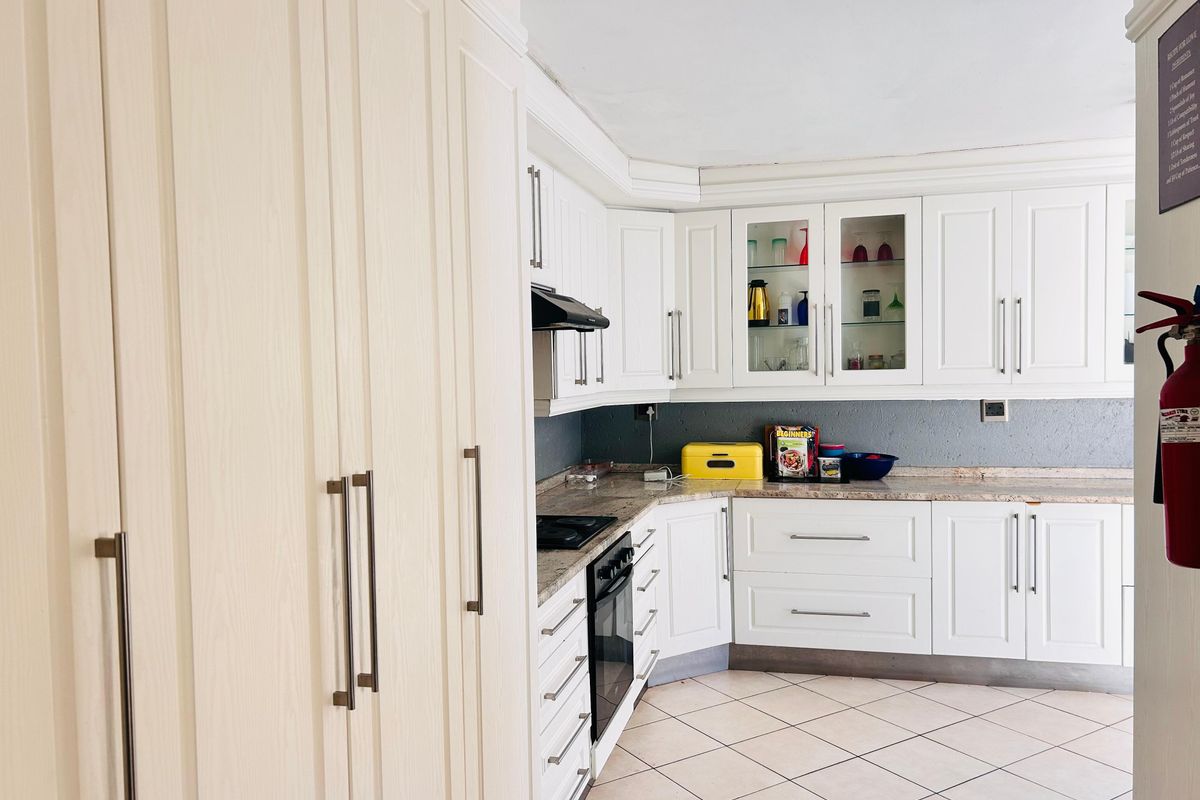 A functional kitchen featuring white built-in cabinetry, granite countertops, integrated appliances, and tiled flooring, offering ample storage and workspace.