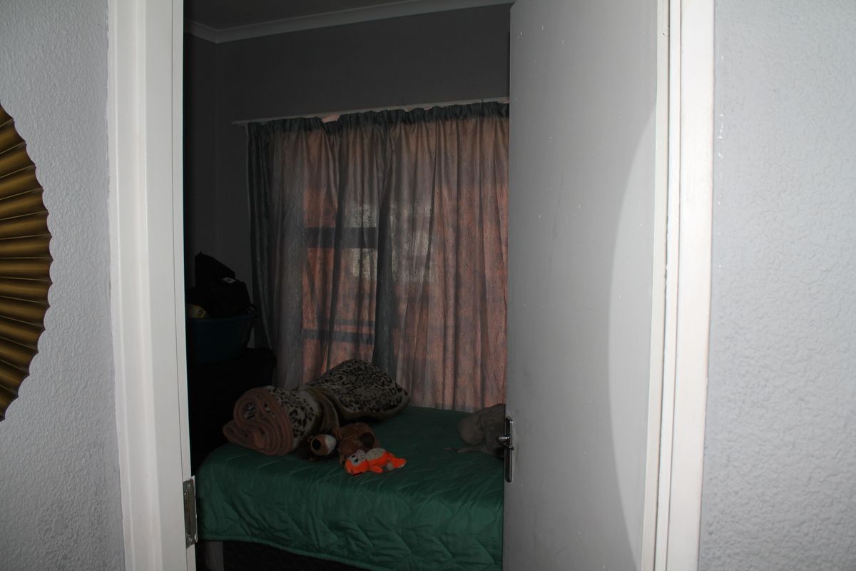 A view into a bedroom featuring a window with curtains, captured from the doorway.