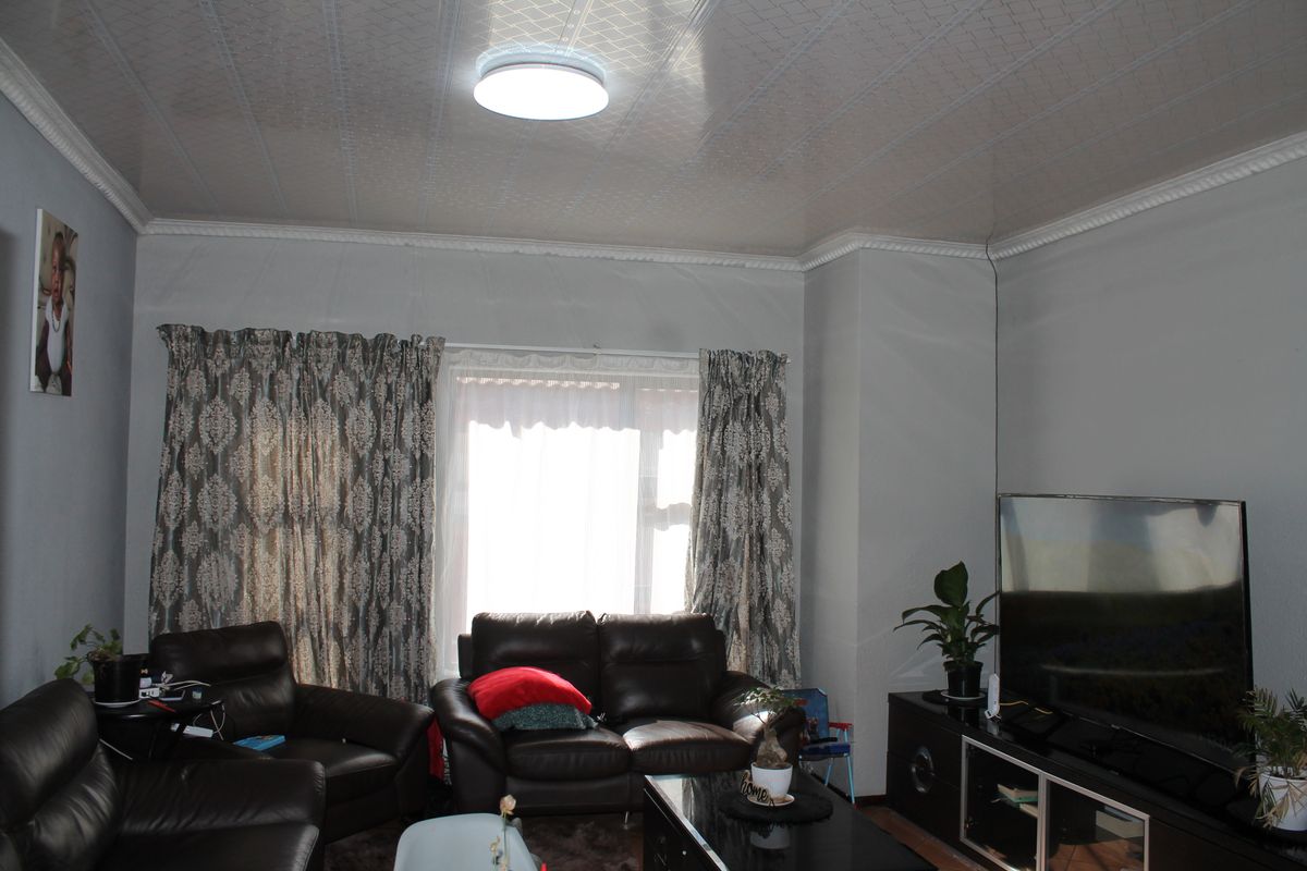 A living room featuring a textured ceiling with crown molding and a central flush mount light fixture.