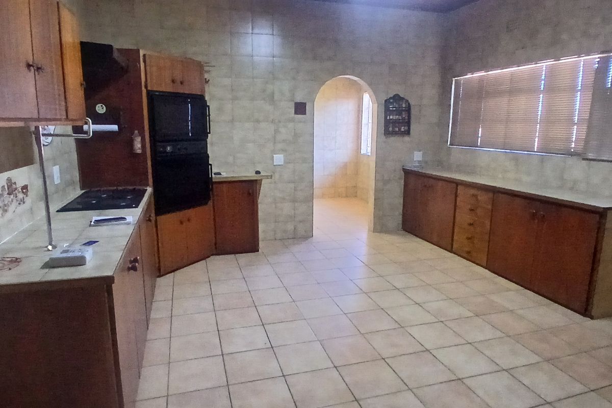Spacious kitchen featuring timber ceilings, tiled flooring, built-in wooden cabinetry, and a double oven, offering a functional layout with potential for modern updates.
