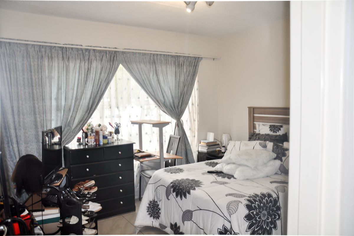 A bedroom featuring tiled flooring, neutral wall finishes, and a window with curtain tracks.
