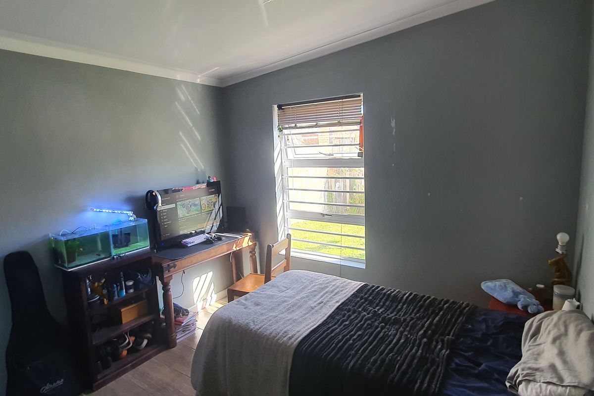 A bedroom featuring grey painted walls, a window with horizontal blinds, and crown molding.