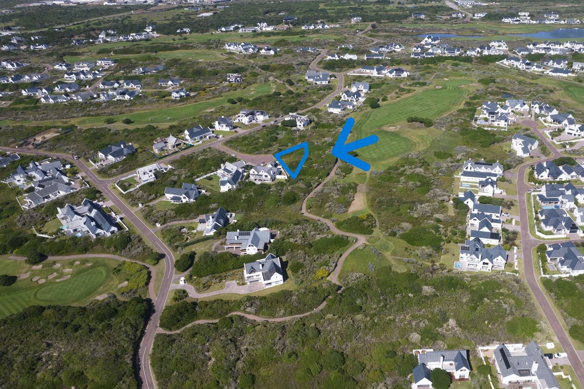Aerial view of a vacant residential plot situated within a coastal golf estate, surrounded by established homes and natural vegetation.