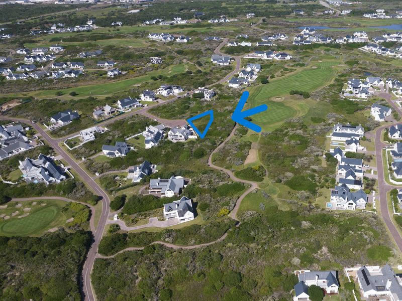 Aerial view of a vacant residential plot situated within a coastal golf estate, surrounded by established homes and natural vegetation.
