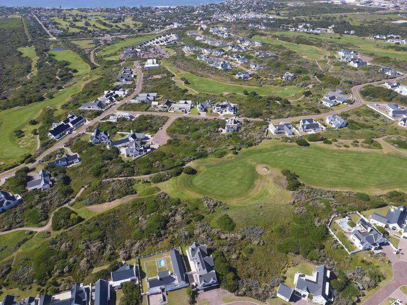 An aerial view of a residential estate featuring well-maintained homes, paved roads, and extensive green spaces including a golf course.