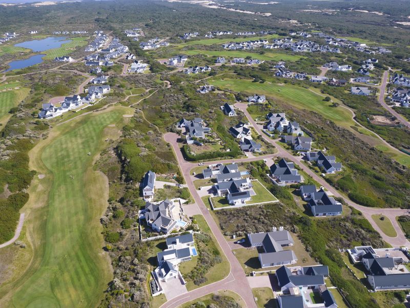 An aerial view of a residential golf estate featuring landscaped fairways, paved road networks, and multiple detached residential properties.