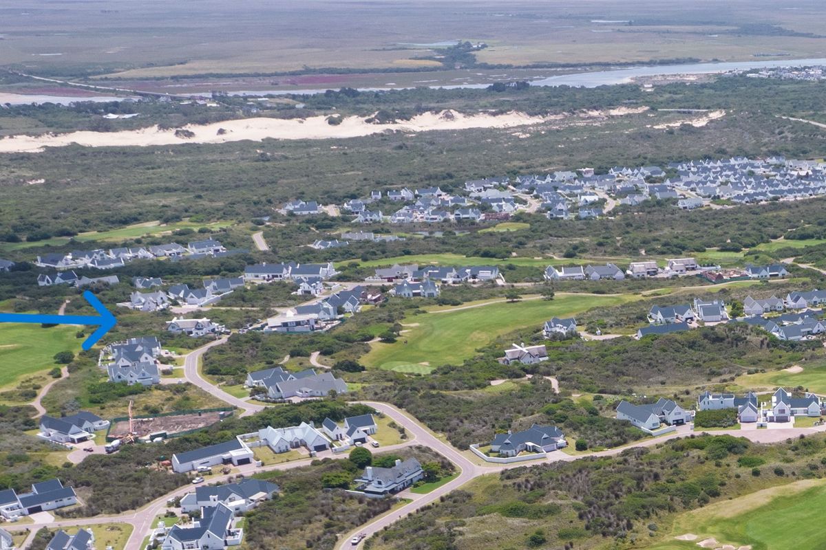 An aerial view of a residential estate situated within a coastal landscape, featuring proximity to a golf course and natural surroundings.
