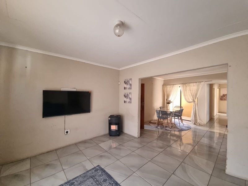 Open-plan living and dining area featuring neutral tiled flooring and coved ceilings, providing a functional space with direct access to the adjoining room.