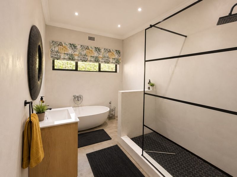 Modern bathroom featuring a sleek walk-in shower with black frame, a contemporary freestanding bathtub, and a stylish vanity unit.