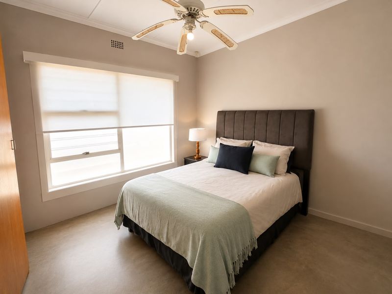 A well-maintained bedroom featuring a ceiling fan, built-in storage, and neutral finishes, providing a comfortable and functional living space.