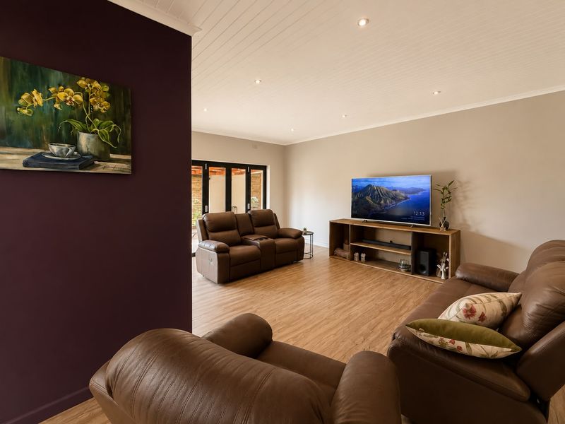 Spacious living room featuring timber laminate flooring, recessed downlighting, and bi-fold doors leading to an outdoor area.