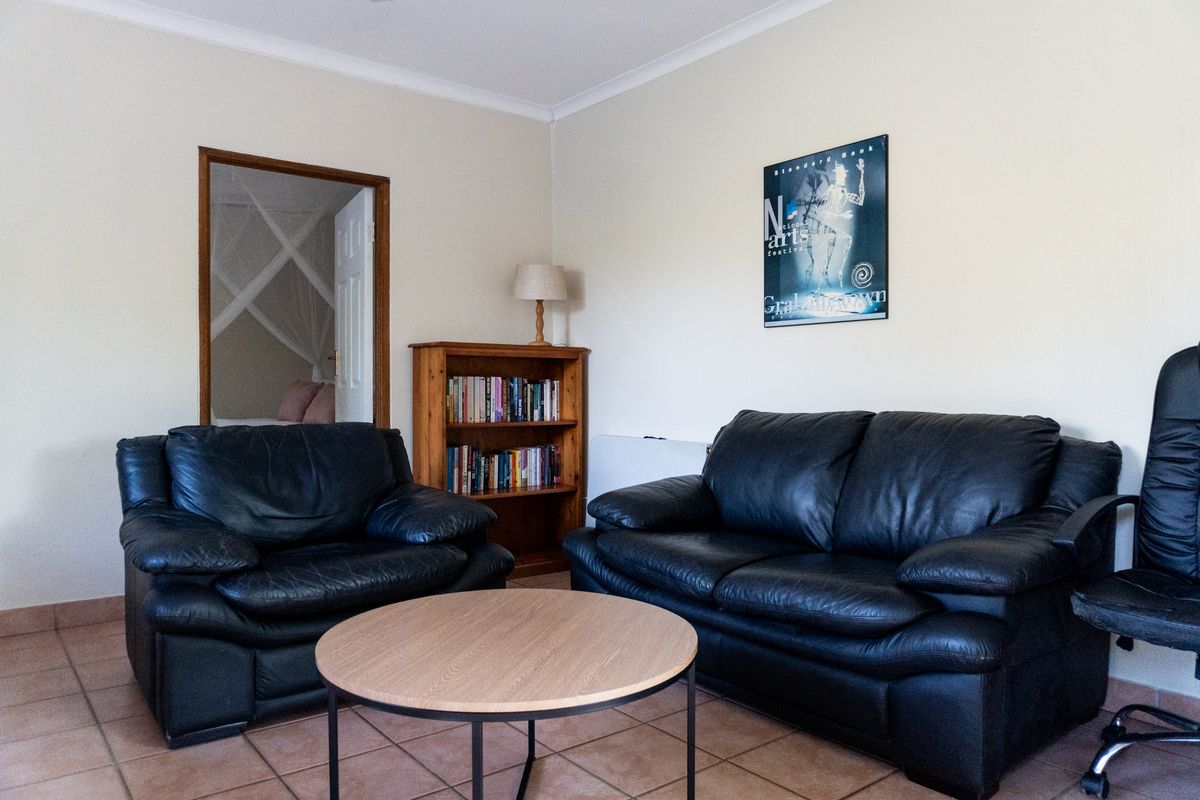 A living room featuring tiled flooring and a doorway leading to an adjacent bedroom.
