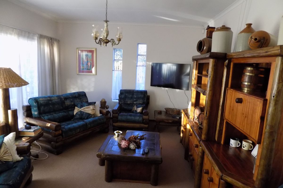 A comfortable living room featuring a coved ceiling, vertical windows, and a central chandelier, providing a functional and traditional living space.