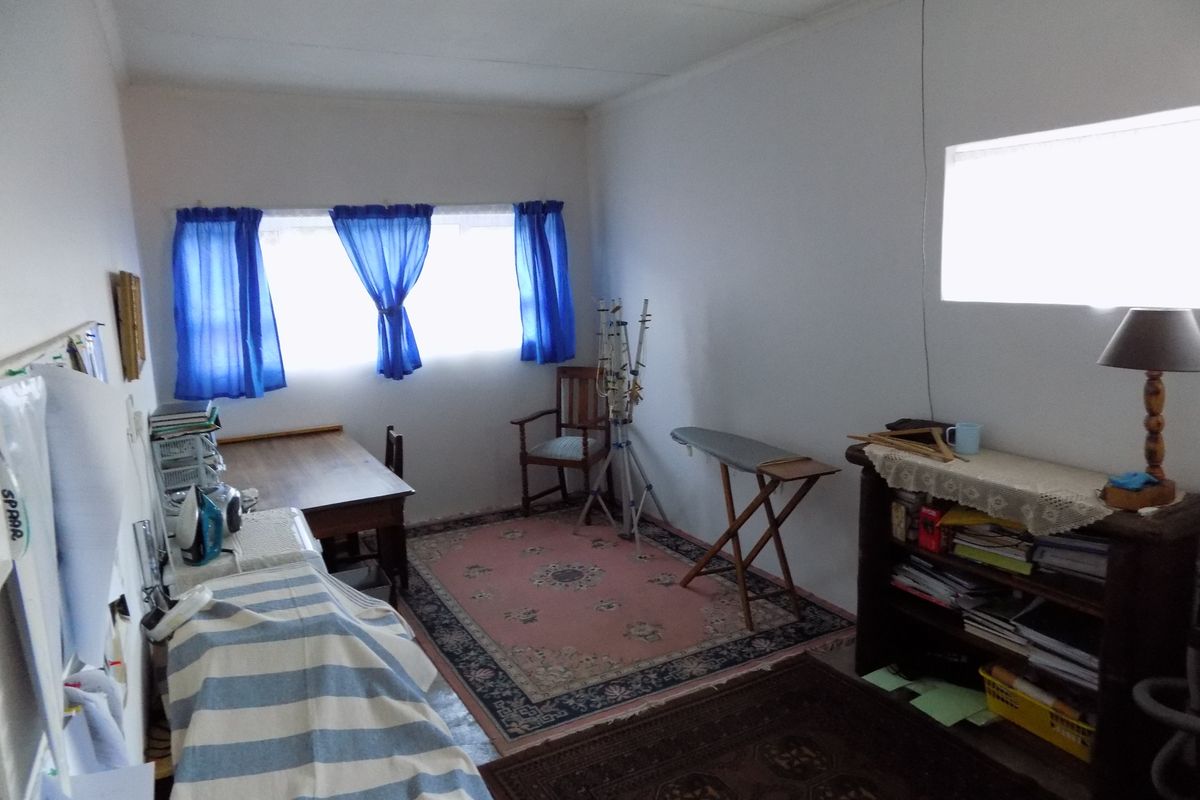 A simple bedroom space with plain white walls and a window, offering a blank canvas for potential renovation or restyling.