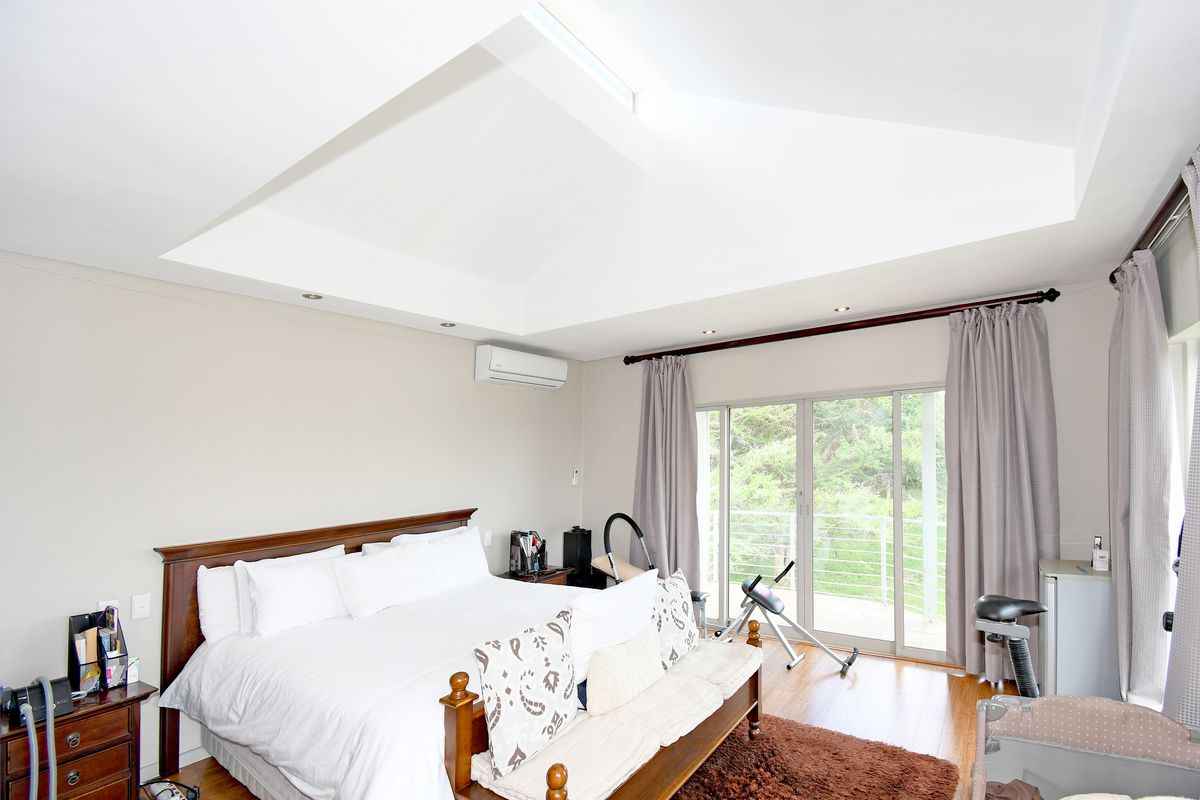 Spacious bedroom featuring a vaulted ceiling, recessed lighting, split-system air conditioning, and sliding glass doors opening to an outdoor balcony.