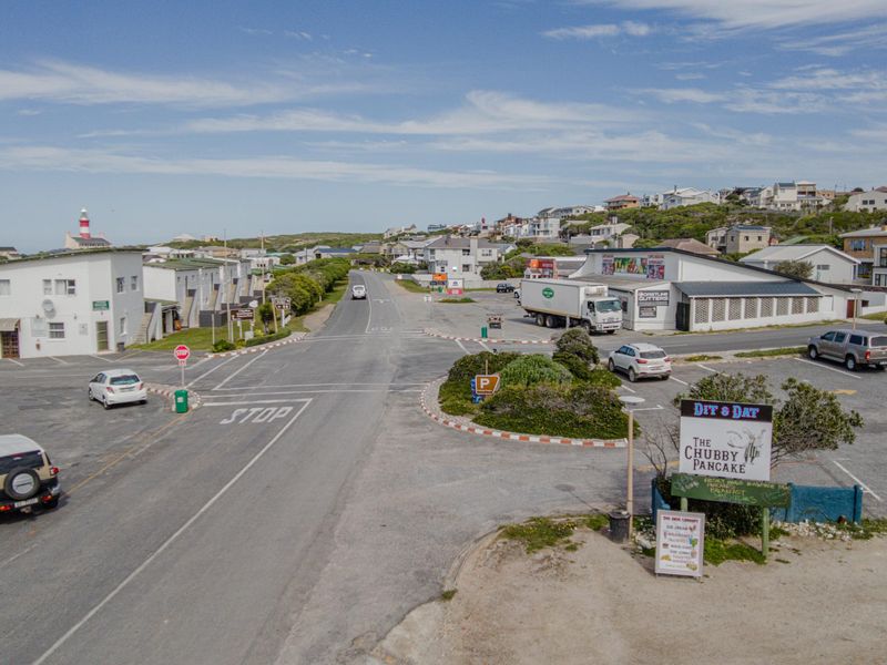 An elevated view of a local street intersection and surrounding commercial parking area in a coastal residential neighborhood.