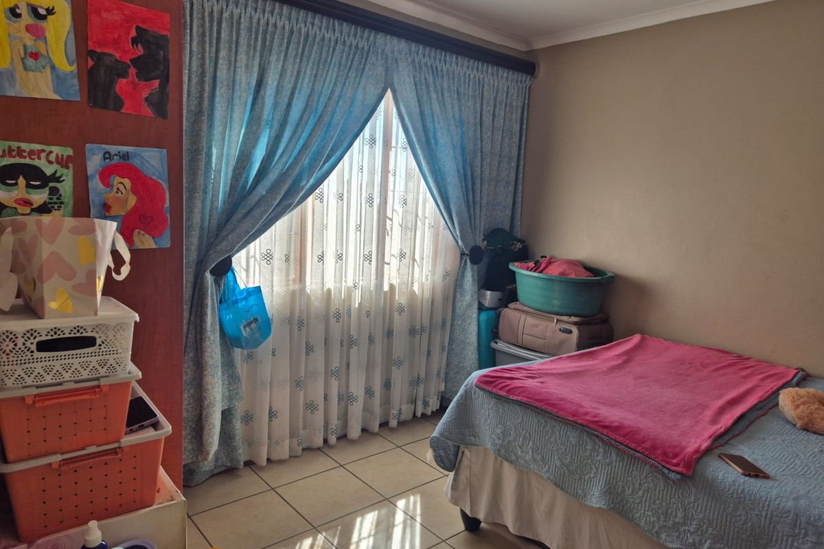 A bedroom featuring tiled flooring and window treatments, providing a functional space with natural light.