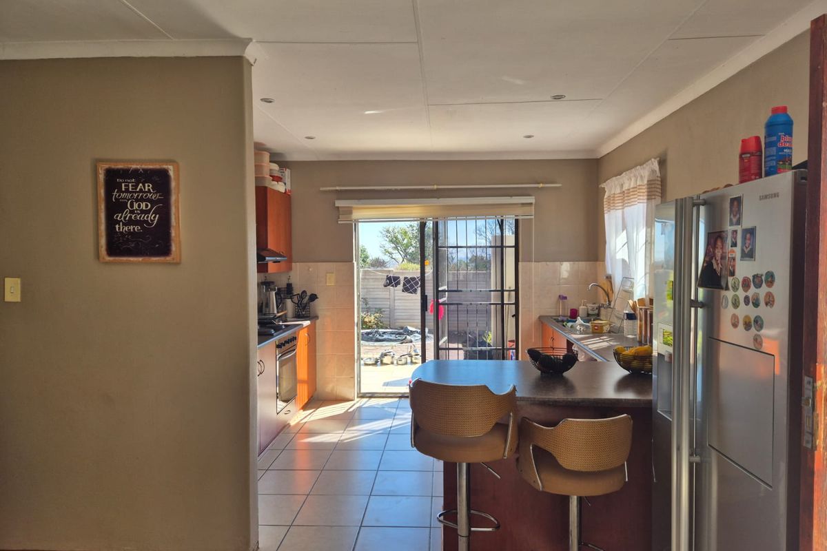 A functional kitchen featuring built-in cabinetry, a central island with breakfast bar seating, tiled flooring, and direct access to the rear patio area.
