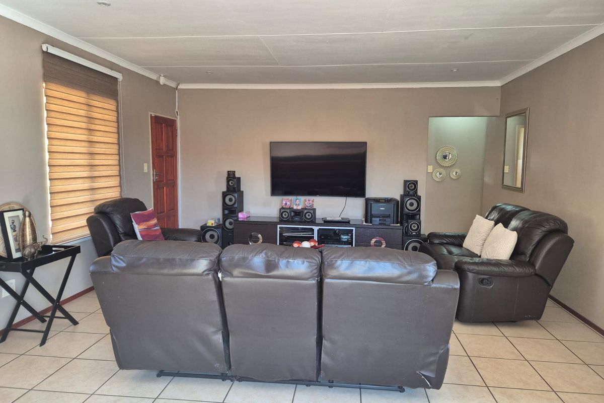 A spacious living room featuring neutral wall tones, tiled flooring, and recessed lighting, providing a comfortable and functional area for relaxation.