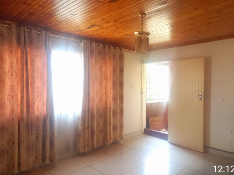 A vacant living room featuring a timber tongue and groove ceiling, ceramic floor tiles, and direct access to an outdoor area.