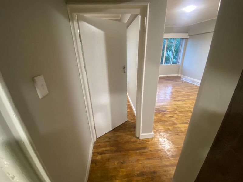 A view from a hallway looking into an empty room featuring polished hardwood flooring and neutral wall finishes.