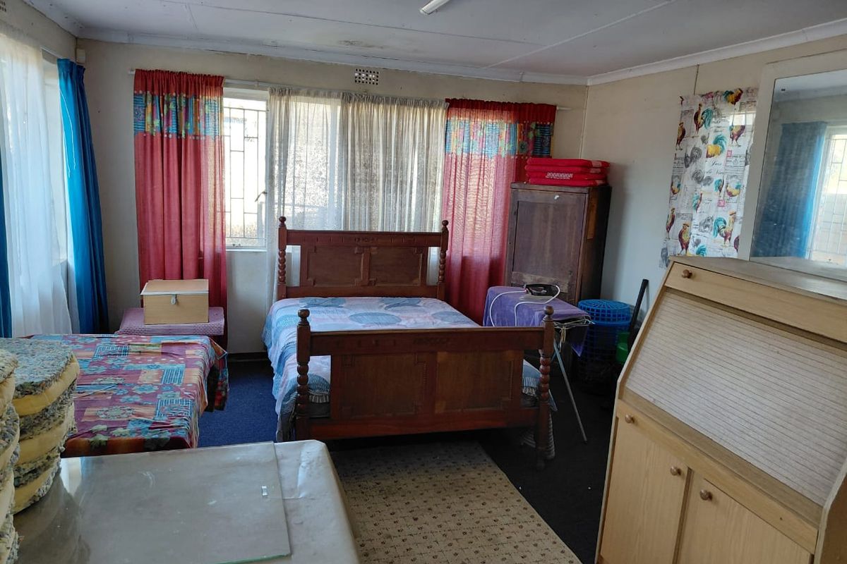 A bedroom featuring a window with security bars and basic interior finishes, offering a functional space for rest.
