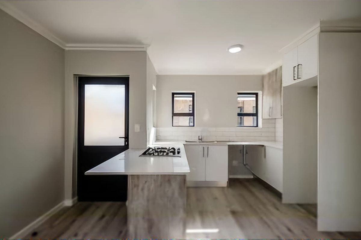 Modern kitchen featuring a central island with a gas hob, white cabinetry, subway tile backsplash, and durable laminate flooring with direct exterior access.
