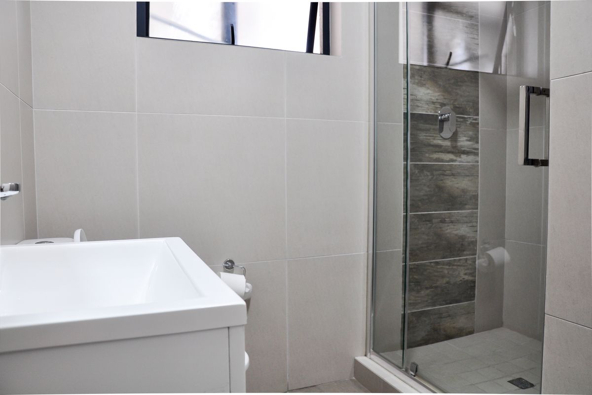 Modern bathroom featuring a glass-enclosed shower with wood-look tile accents, a contemporary vanity, and neutral wall tiling.