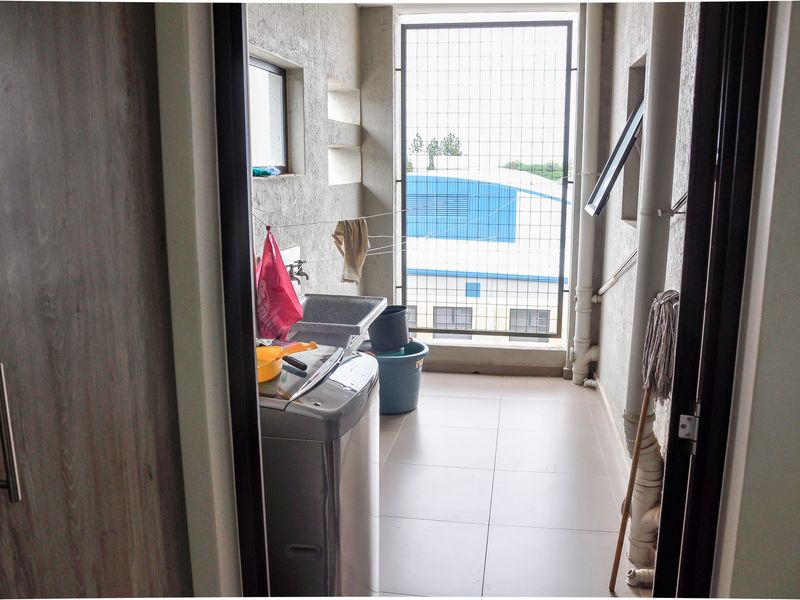 A functional laundry area featuring tiled flooring, a utility sink, and external security screening, providing a practical space for household chores.