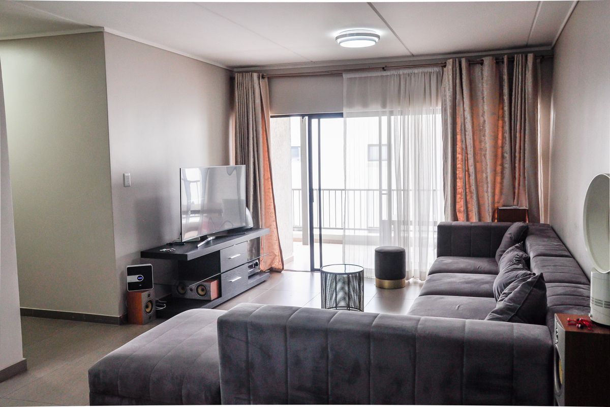 A comfortable living room featuring tiled flooring and a sliding glass door that opens onto a private balcony, providing natural light.