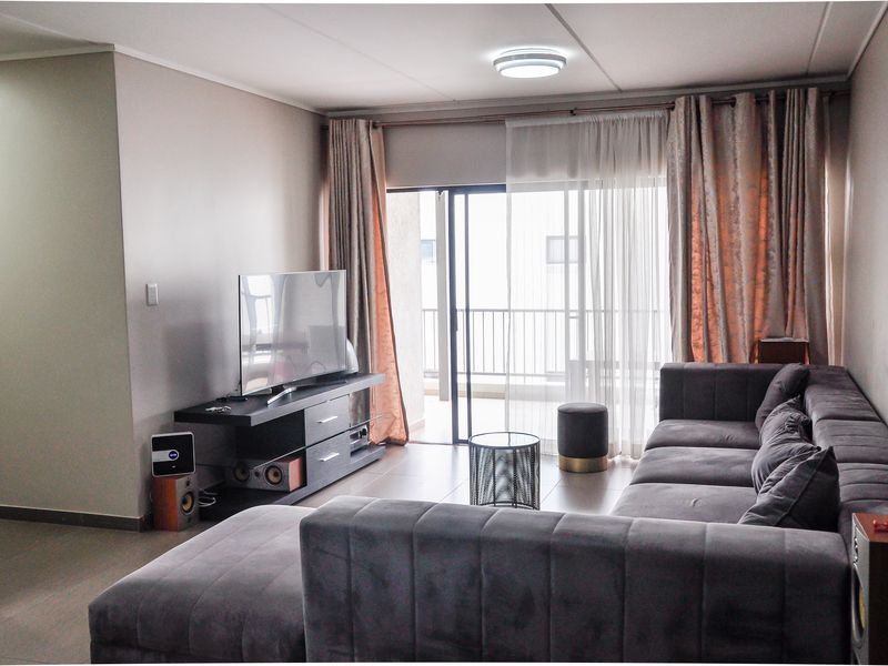 A comfortable living room featuring tiled flooring and a sliding glass door that opens onto a private balcony, providing natural light.