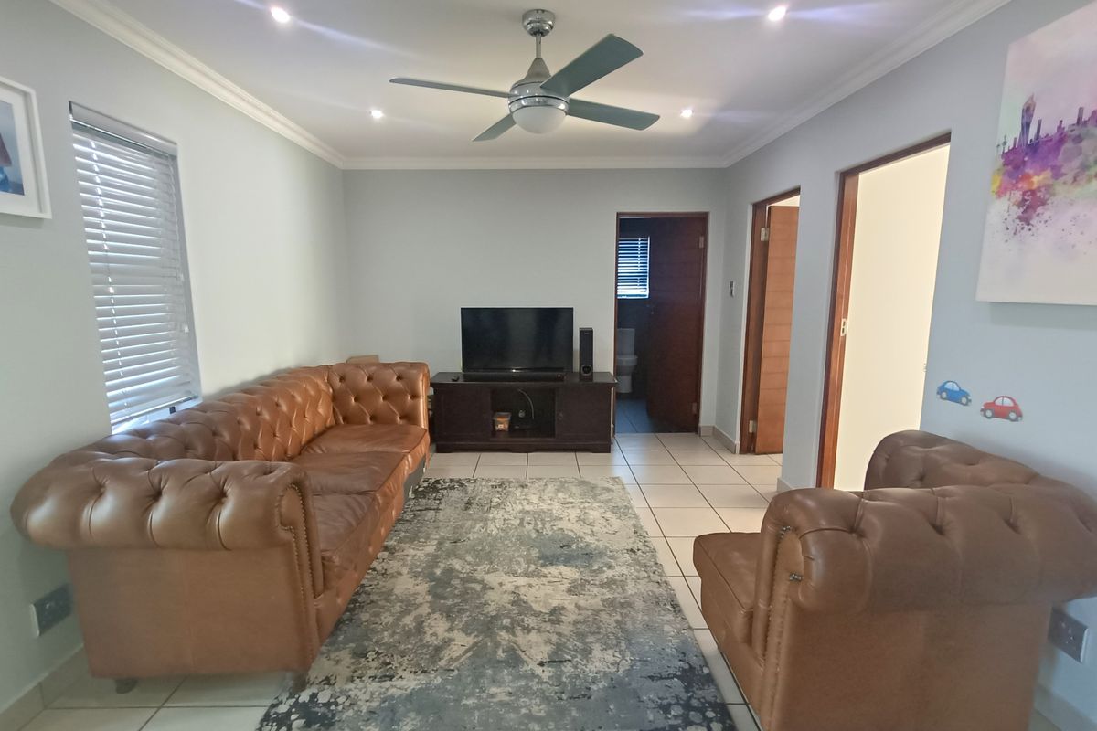 A well-maintained living room featuring ceramic floor tiles, recessed downlighting, and a ceiling fan, providing a functional and comfortable space.