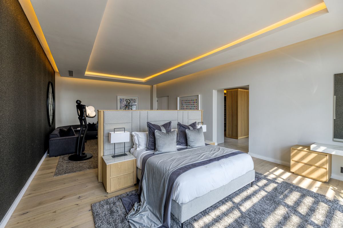 Spacious master bedroom featuring recessed ceiling lighting, integrated headboard with built-in nightstands, and access to a walk-in closet area.