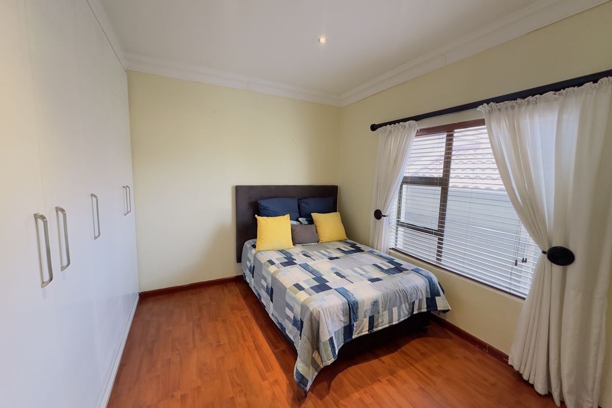 A well-maintained bedroom featuring laminate flooring, built-in cupboards, and recessed downlighting, offering a clean and functional living space.