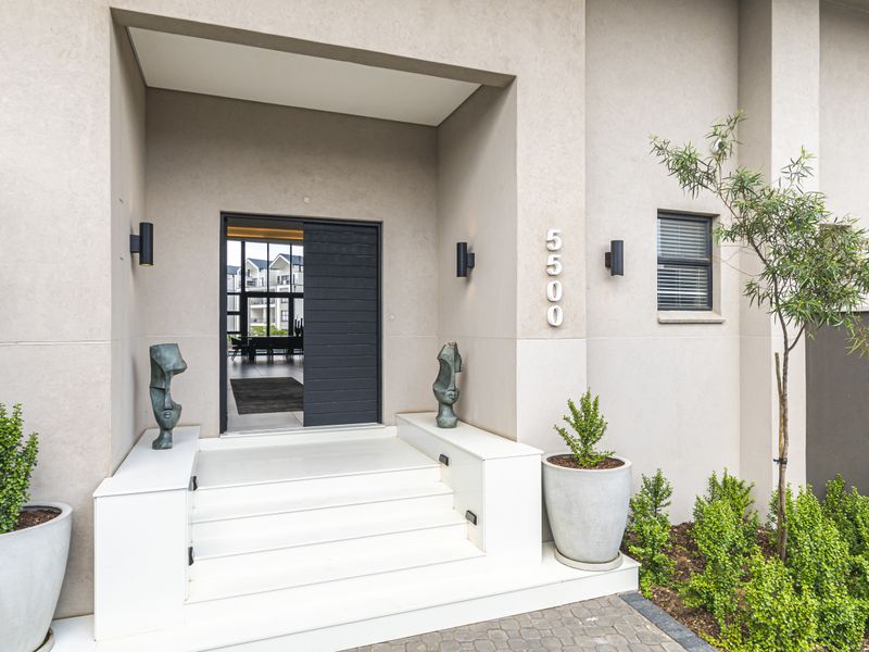 Modern apartment entrance featuring a sleek dark horizontal-slat front door, elevated white concrete steps, and contemporary wall-mounted exterior lighting.