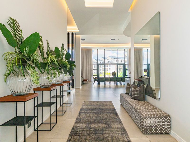 Spacious and modern entrance hall featuring high ceilings, recessed lighting, and large format floor tiles, leading into an open-plan living and dining area.