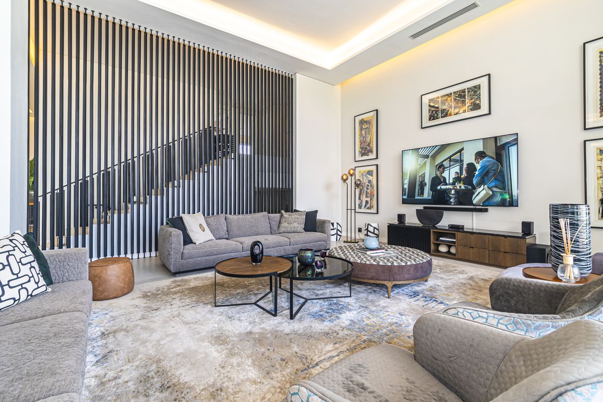 Spacious living room featuring a striking vertical slat room divider, recessed ceiling lighting, and a modern open-plan layout.
