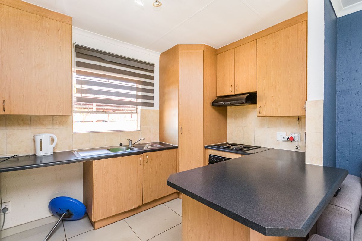Functional kitchen featuring laminate cabinetry, dark countertops, built-in oven with extractor fan, and tiled flooring, offering a practical layout for daily use.