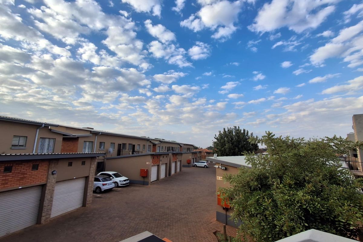 An elevated view of the apartment complex rear courtyard featuring paved driveway access and multiple garage units.