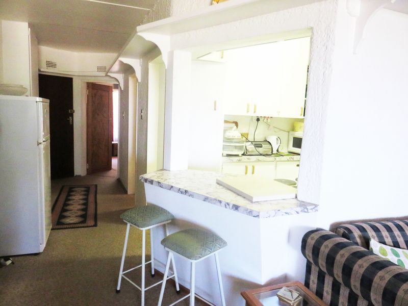 Open plan living area featuring a breakfast bar pass-through to the kitchen, with access to internal hallways and rooms.